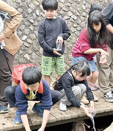 アユを放流する子どもたち＝同会提供