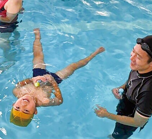 ペットボトルを持って水に浮く参加者