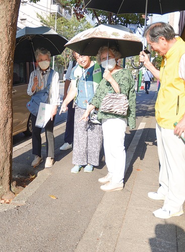 暑い中、日傘を差しながら危険な場所を見回る参加者
