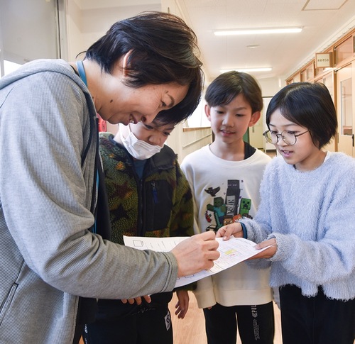 五十嵐校長（左）にスタンプをもらう児童