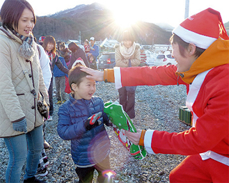 現地のＮＰＯの活動でサンタに扮して子どもたちにプレゼントを配る富山さん