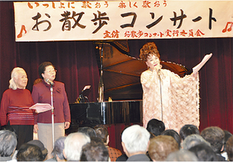参加者と熱唱する古渡さん（右）