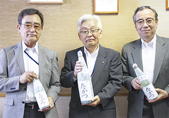 土方区長（中央）に純米酒「たかつ」を贈呈した森支部長（左）、大竹さん