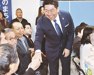 当選確実の一報を受け、支援者と握手を交わす福田氏＝22日午後８時過ぎ