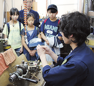 卓上旋盤で真鍮を削る工程を見学する子どもたち