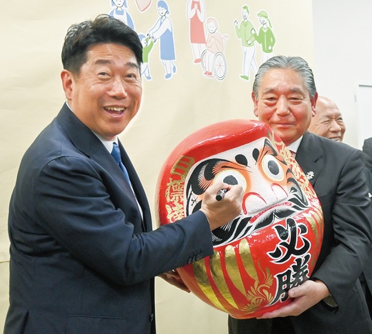 だるまに目入れをする福田氏（左）