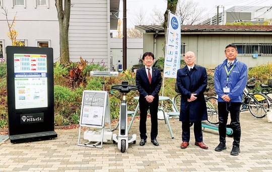 デジタルサイネージやシェアサイクルと共に、実証実験の関係者ら