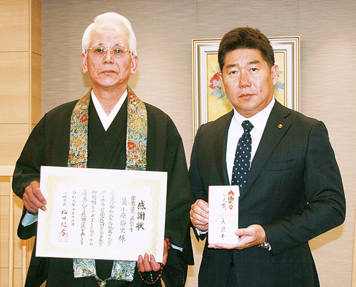 川崎市長に寄付した眞宗寺の小原住職（左）