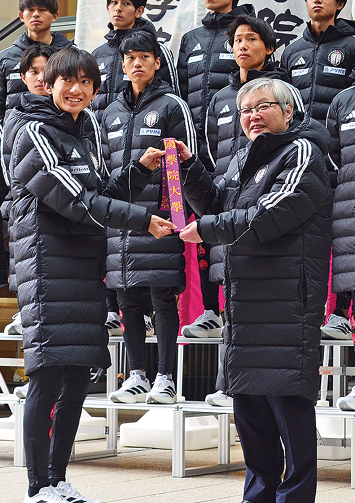 針本正行学長（右）から襷を受け取る主将の平林清澄選手