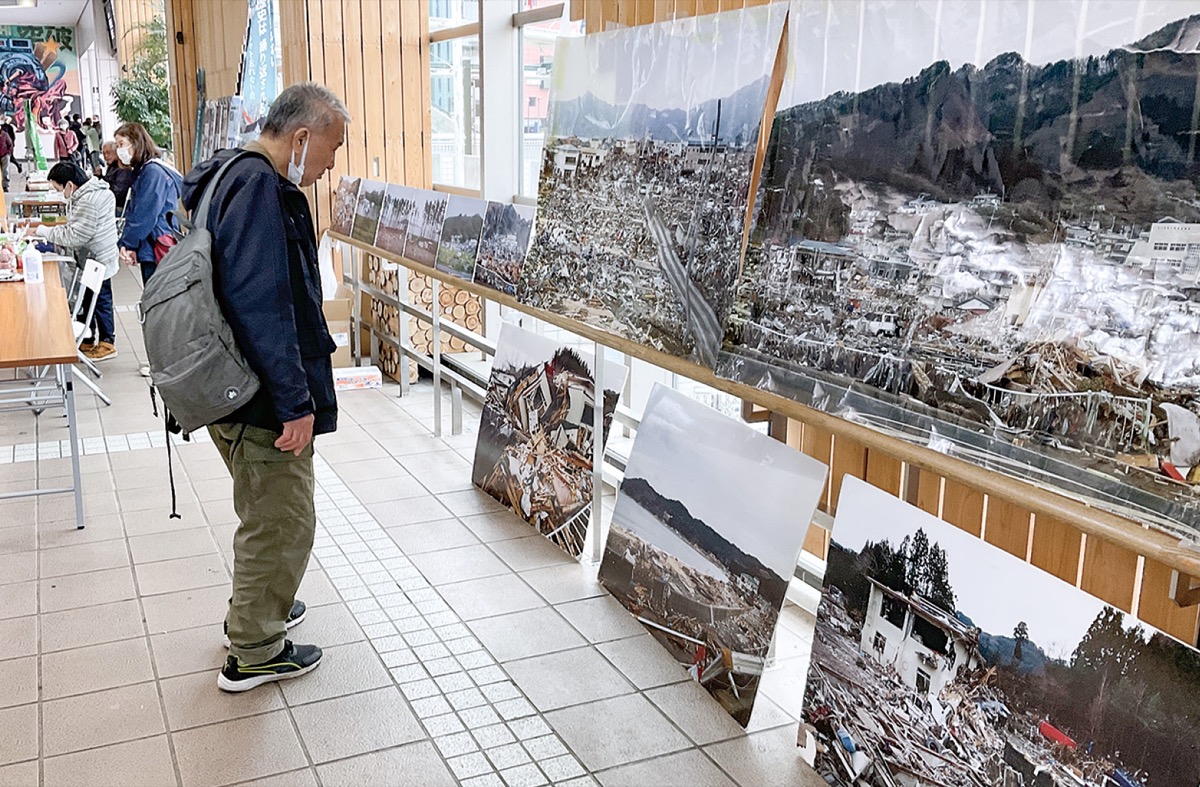 当時の写真に見入る通行人