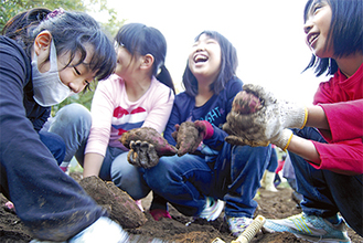 掘り当てたサツマイモを嬉しそうに手に取る子どもたち