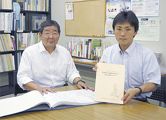 決算カードを開く江井理事長（左）と白書を手にする村松秀幸事務局長