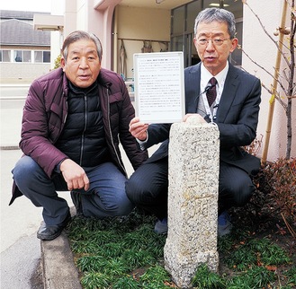 児童の玄関前に設置された基標と小川さん（左）、解説の案内板を手にする千野校長＝１月15日