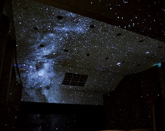 多摩市民館大ホールの天井や壁面に映し出された星空