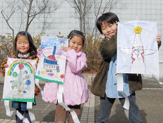 （左から）岡本太郎作品「こどもの樹」「マミ会館」「太陽の塔」をモチーフに描いた自作の凧を持つ子どもたち