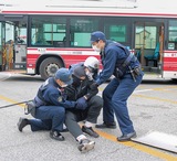 バスから出てきた犯人役の男性を取り押さえる警察官