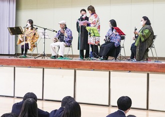 生徒の前で演奏を披露する前浜さん(左から２人目)と家族や仲間