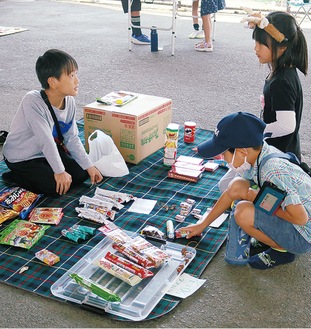 駄菓子屋で店番をする児童（左）