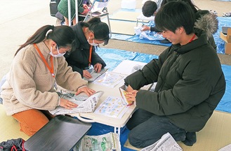 紙食器を作る参加者（左）