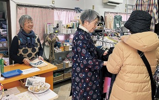 店を訪れた人に商品を紹介するメンバーと鈴木代表（左）＝３月21日