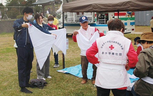 三角巾の使用法を教える横山委員長（中央）