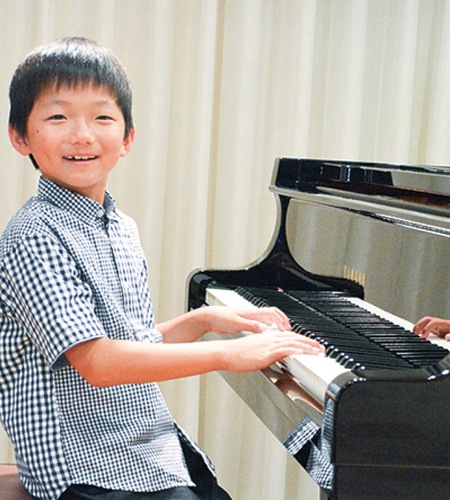 ピアノを前に笑顔の小山さん