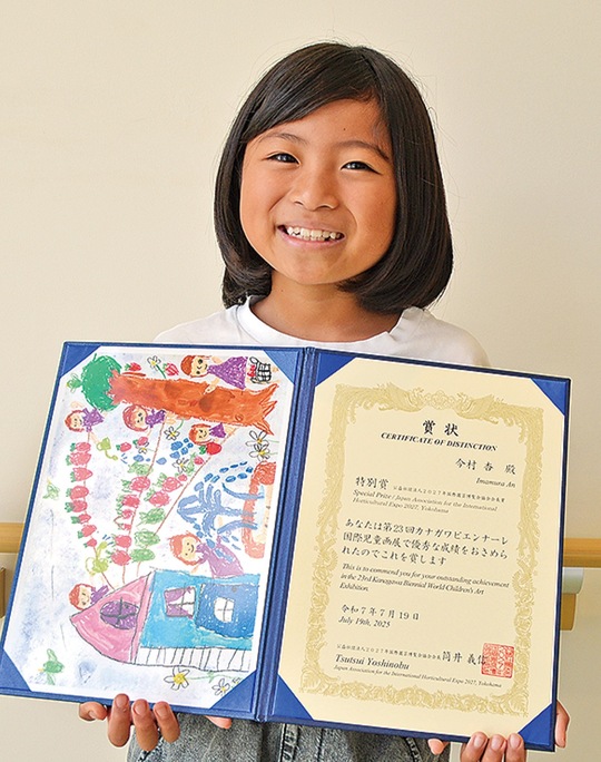 作品のコピーと賞状を手にする今村さん