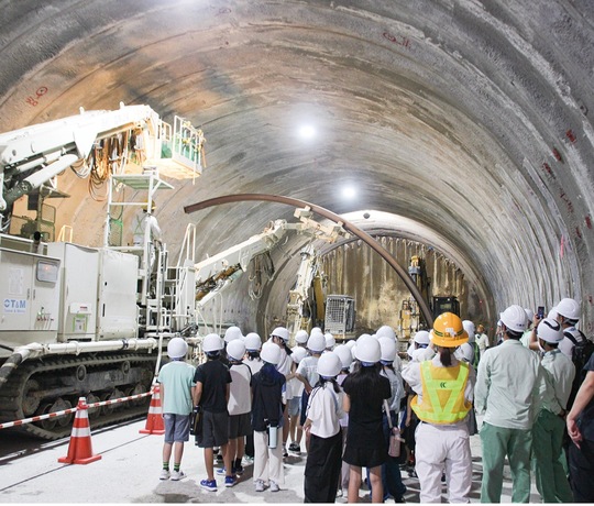 トンネル内で重機の説明を受ける児童ら
