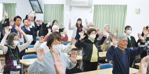 講師の動きを真似しながら体操をする参加者