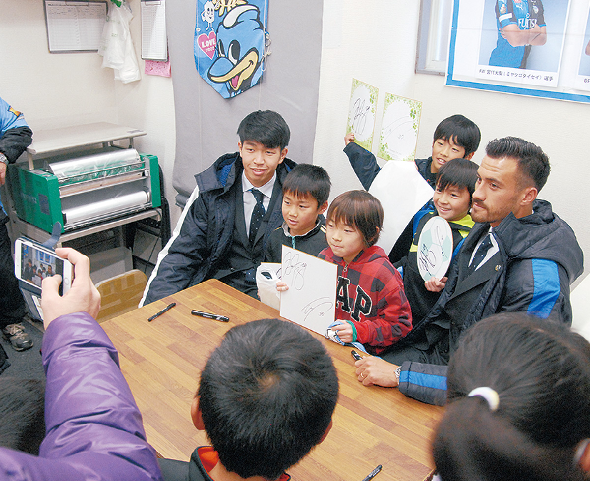 長沢商店会のサイン会で交流するジェームズ選手（右）、宮代選手