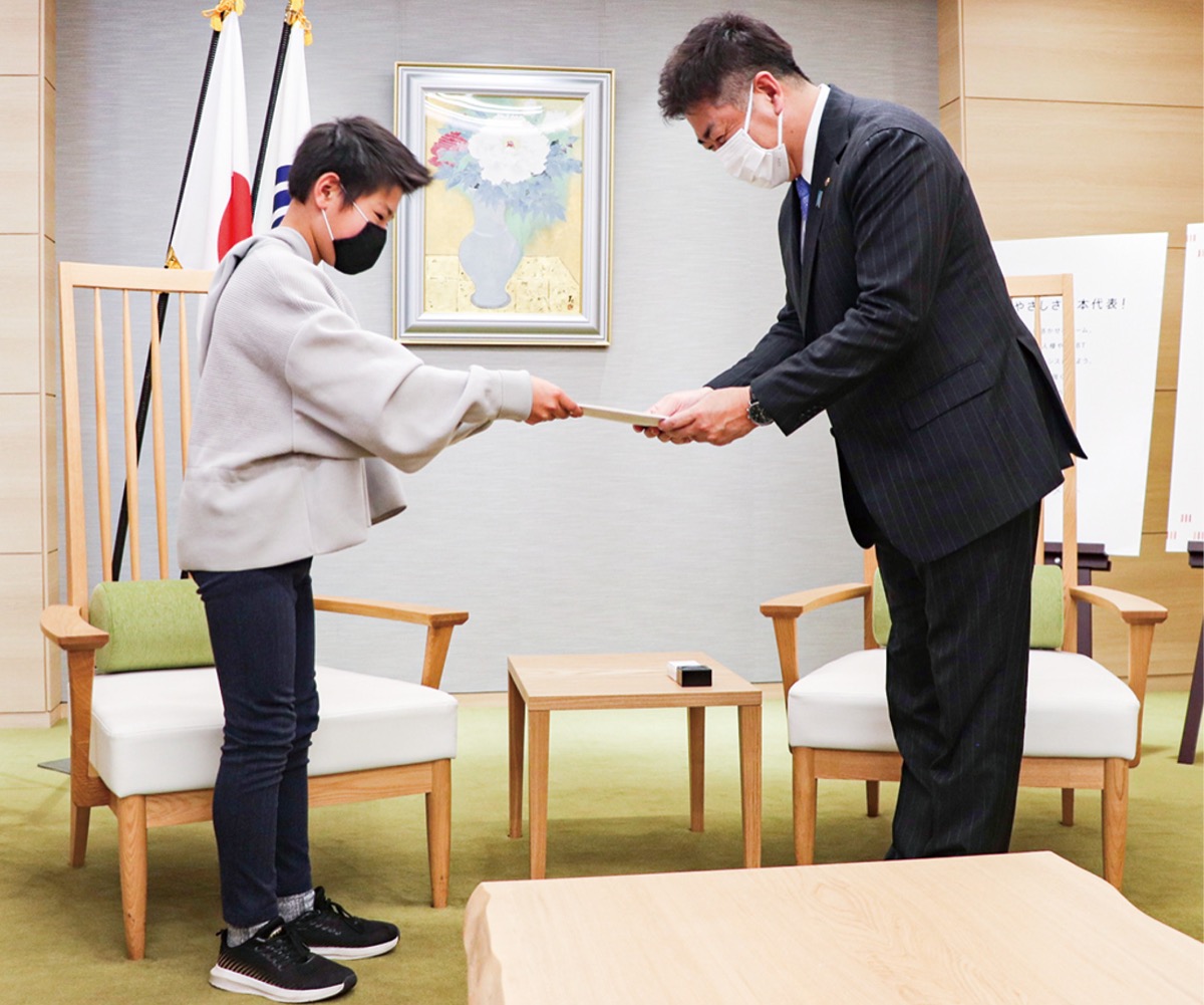 署名を市長に手渡す岡田さん=市提供