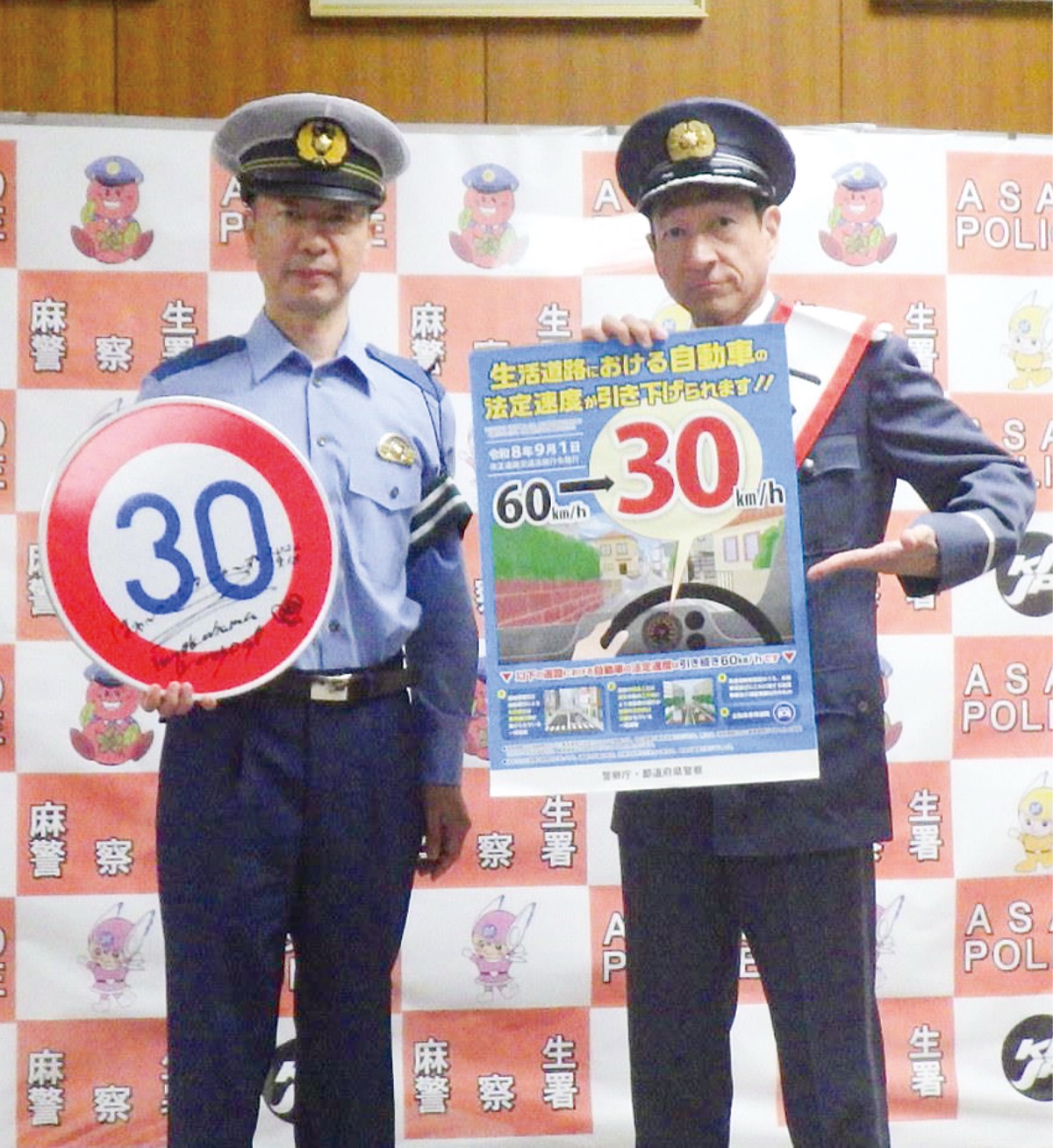ポスターを持つ藤田さん(右)とサイン入り交通標識を持つ倉田文二署長