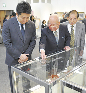 福田市長（左）に展示品を説明する斎藤委員長（中央）