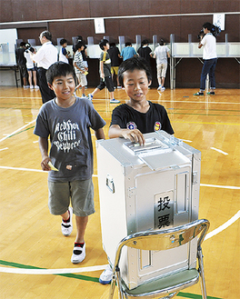実際の投票箱に用紙を入れる児童