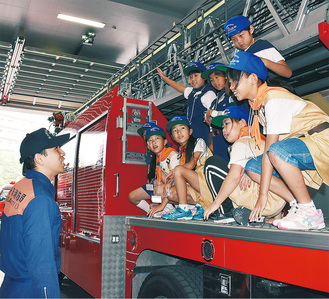 はしご車に乗り、消防署員の解説を受ける児童ら