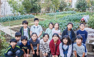 菜園を背に立つ学童の子どもたち
