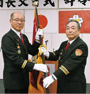 三上団長(右)から団旗を受け取る鹿島新団長