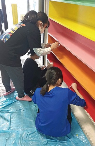 げた箱にペンキを塗る学生たち