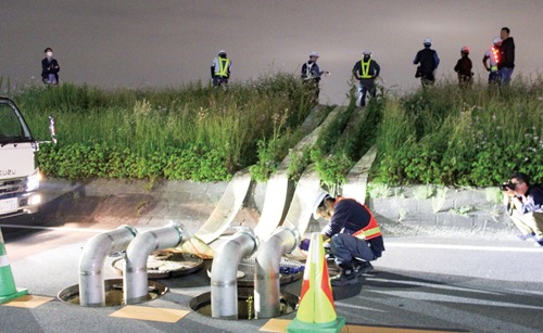 マンホールから排水作業をする職員