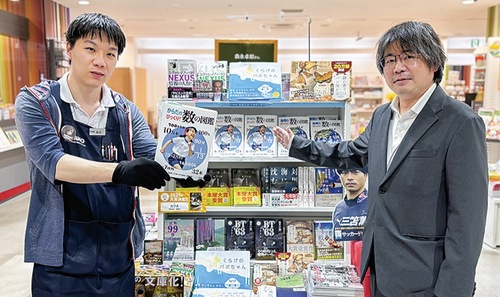 図鑑を手にする書店販売員＝北野書店