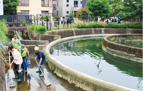 円筒分水の中や周囲を清掃する児童ら