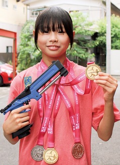 金メダルと愛用のスポーツピストルを手にする志村さん