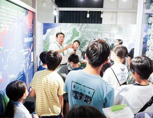 10代の参加者に向け資料館の展示を説明する山田館長（中央）
