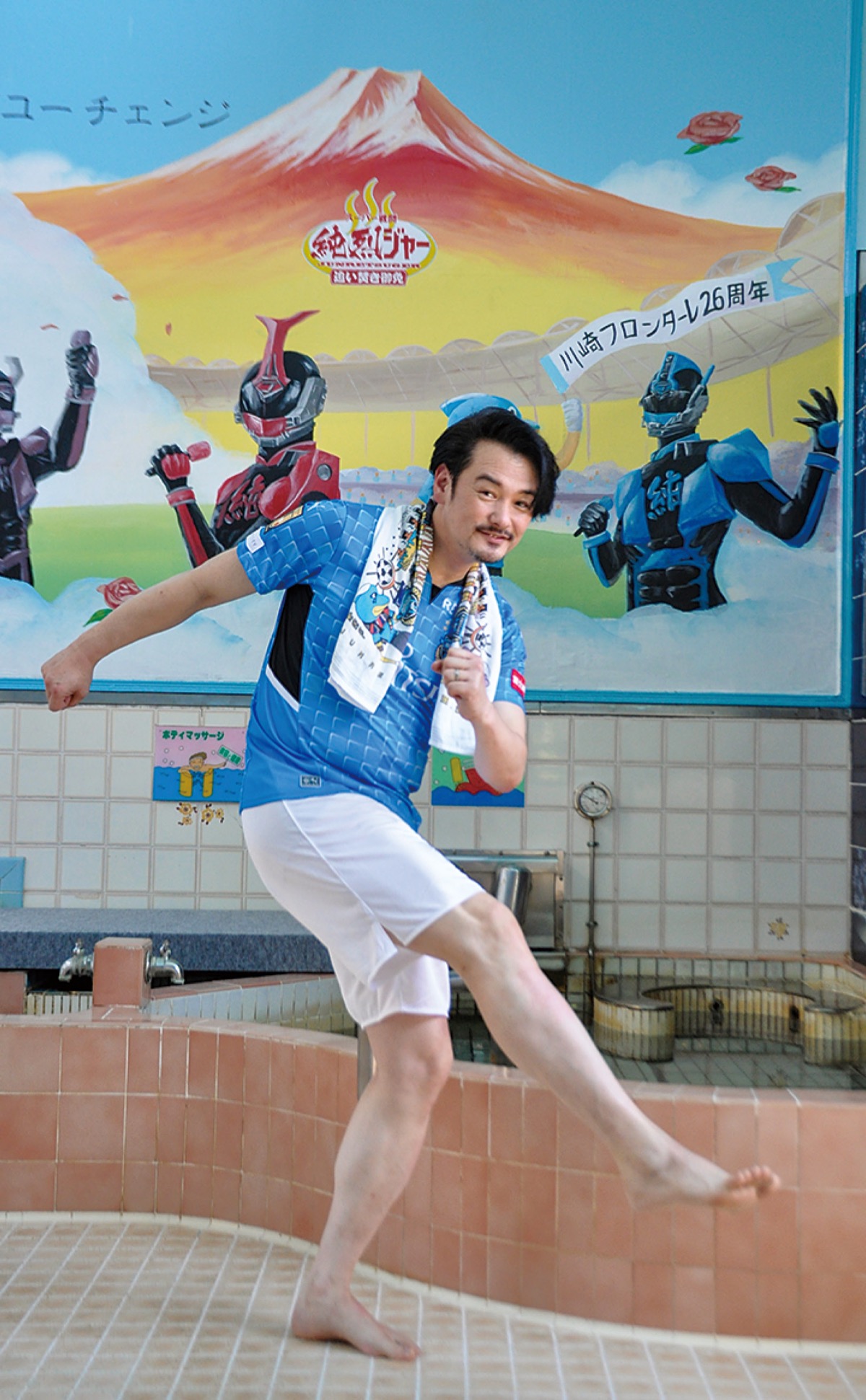 銭湯壁画を背景にユニフォーム姿で映る小田井さん