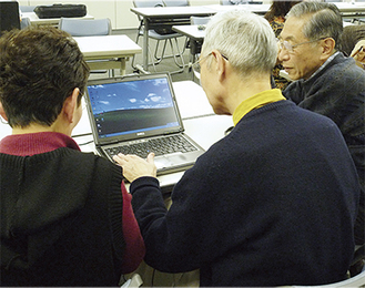 サポーター（右）の指示でキーボードを打つ参加者（中央）