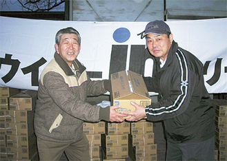 三浦会長（右）から商品を受け取る吉水清事務局長（左）