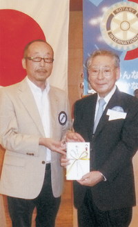 寄付金を手渡す鈴木会長（左）と世界こども財団の土屋了介理事長