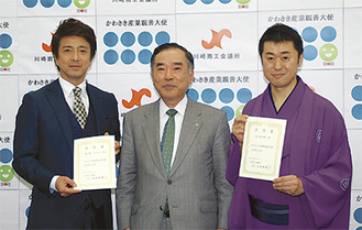 大使に任命された米多朗さん（右）と風間さん（左）。中央は山田会頭