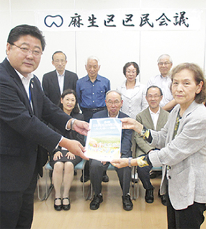 多田区長（左）に報告書を手渡す同区民会議の菅原敬子委員長