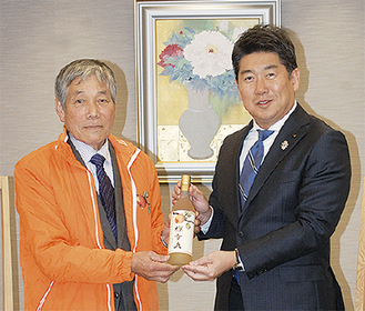 福田市長に今年のワインを手渡す飯草会長（左）
